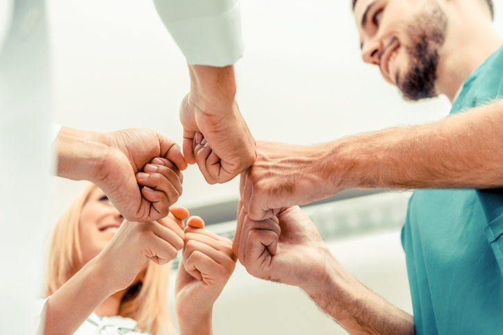 Doctor, surgeon and nurse join hands together.