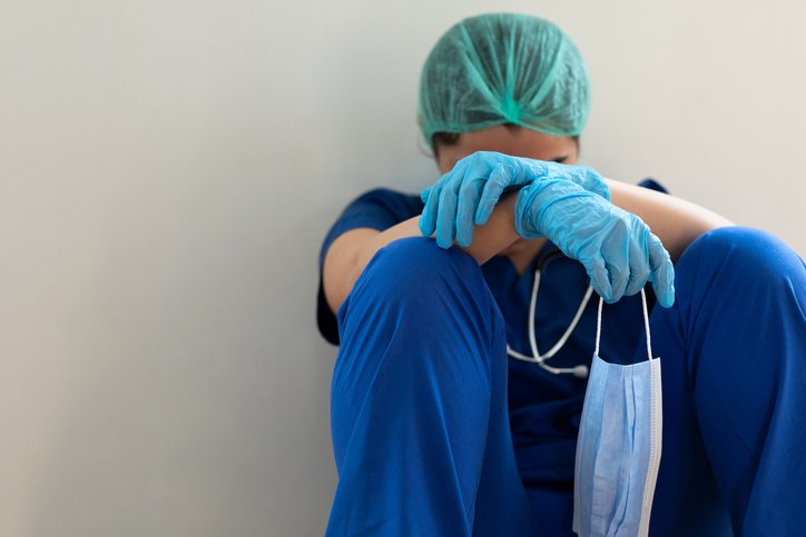 Stressed tired healthcare worker sitting on floor