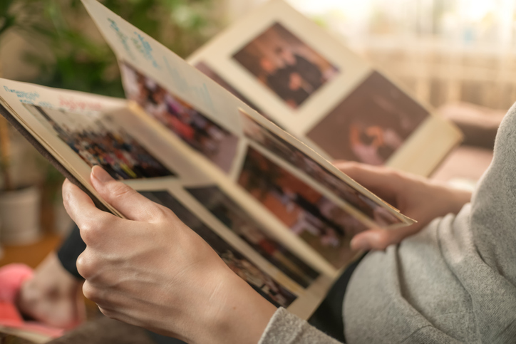 girl in a gray jacket is sitting on the sofa and looking at old photos in a photo album