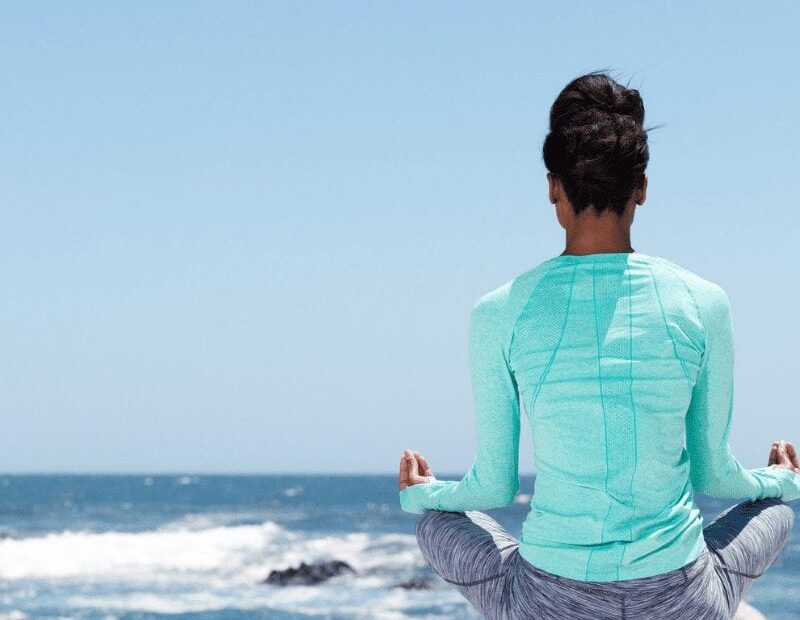 woman meditating on the beach