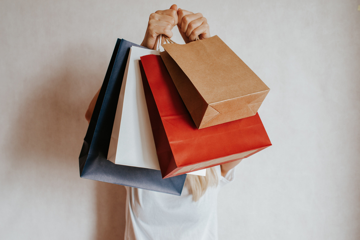 Happy woman holding in hand shopping package. Paper bag. Sale in store. Beautiful young girl in fashion shop. Customer buy present. Black friday sale. Holiday special offer, discount. Female in market