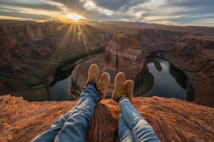 Personal perspective of two people relaxing on top of Grand Canyon