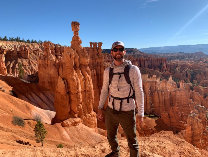 Man in backpacking gear standing in front of red rock landscape