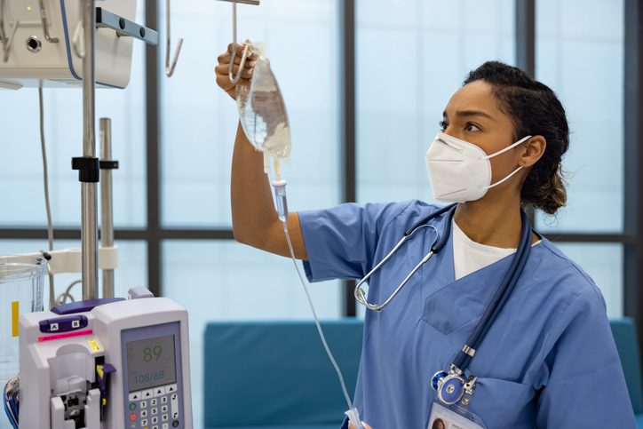 African American nurse at the hospital putting an IV Drip on a patient - healthcare and medicine concepts