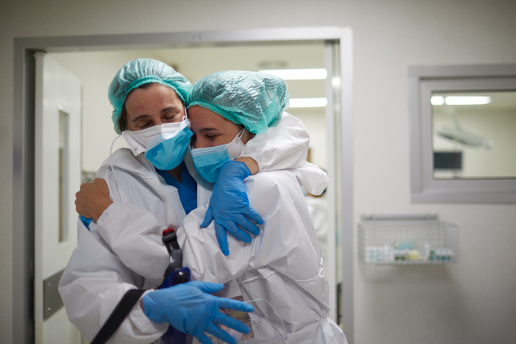 Two healthcare workers hug in celebration of a successful surgery procedure