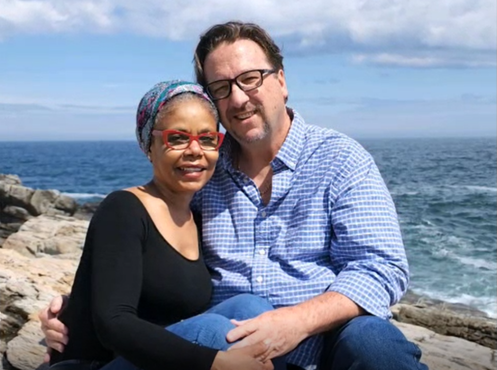 Debbie and her husband posing on the coast of Maine