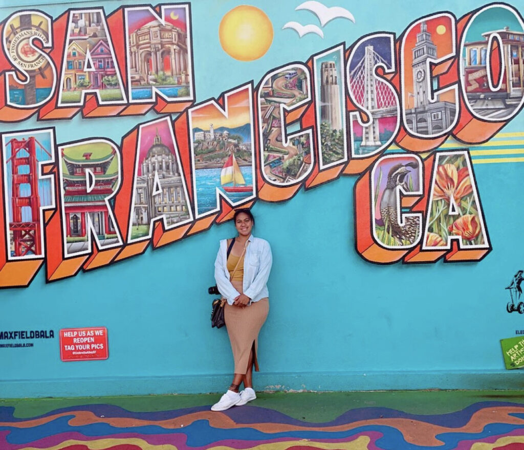 Justine TNAA traveler standing in front of a San Francisco mural