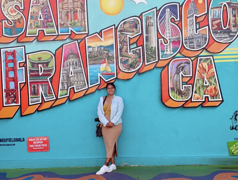 Justine TNAA traveler standing in front of a San Francisco mural
