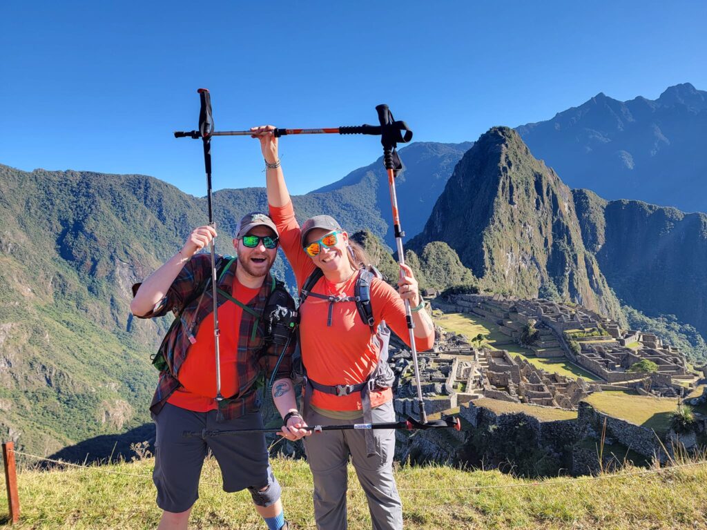 Travel nurses Zane and Ally posing with hiking poles in front of Machu Picchu