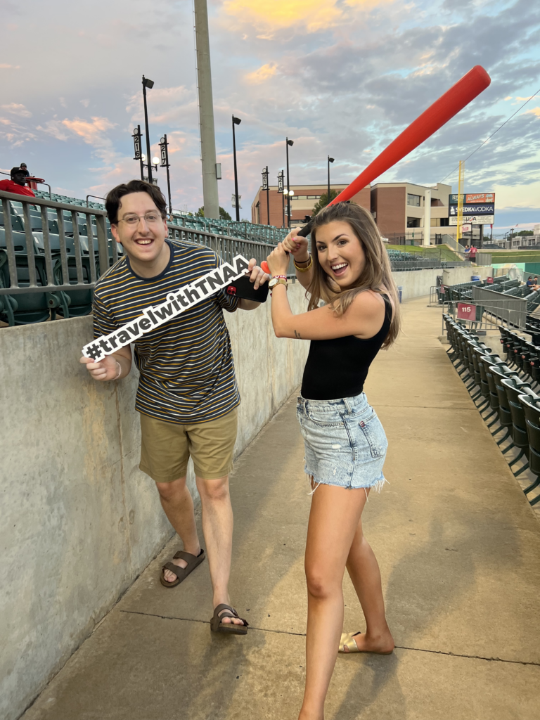 TNAA ambassadors posing with baseball bat and sign at an Arkansas Travelers game