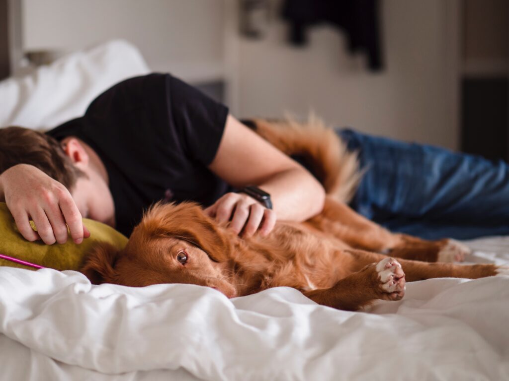 man sleeping next to his small dog