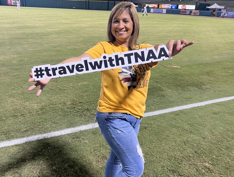 TNAA ambassador and travel nurse holding sign on baseball field