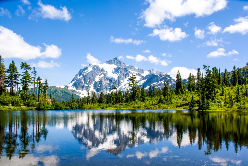 Alpine lake reflecting snow-capped peaks and evergreen forests in North Cascades National Park, Washington