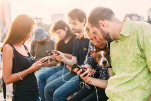 Group of young people on their cell phones with a dog.