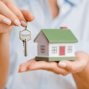 Hands holding miniature house and a house key.