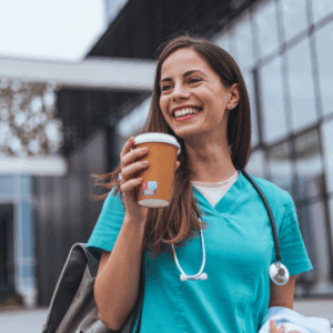 Nurse wearing scrubs and holding a to-go coffee cup.